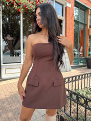 Woman wearing dark brown tailored mini dress with front pockets and built in shorts. 