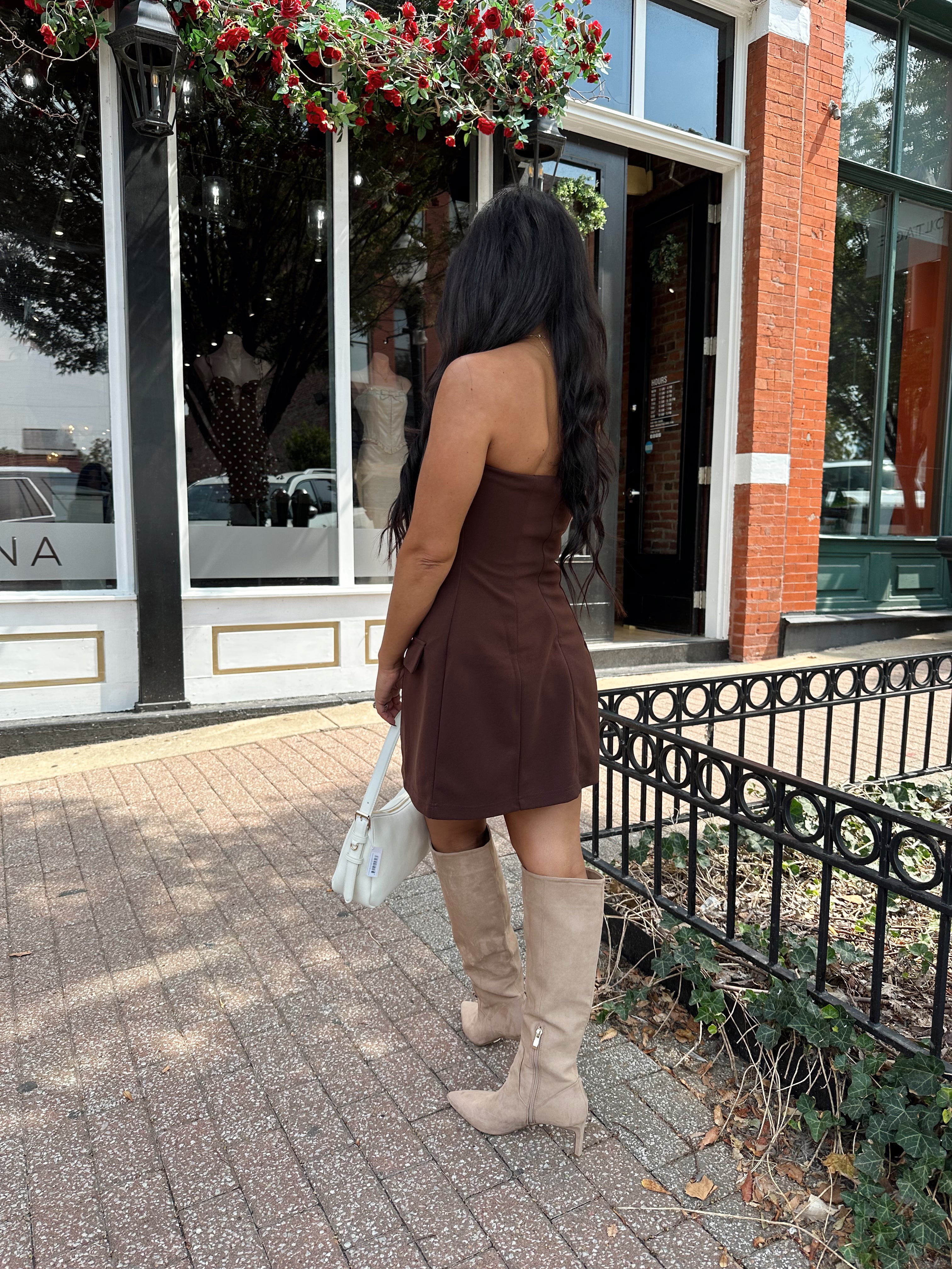 Woman wearing dark brown tailored mini dress with front pockets and built in shorts. 