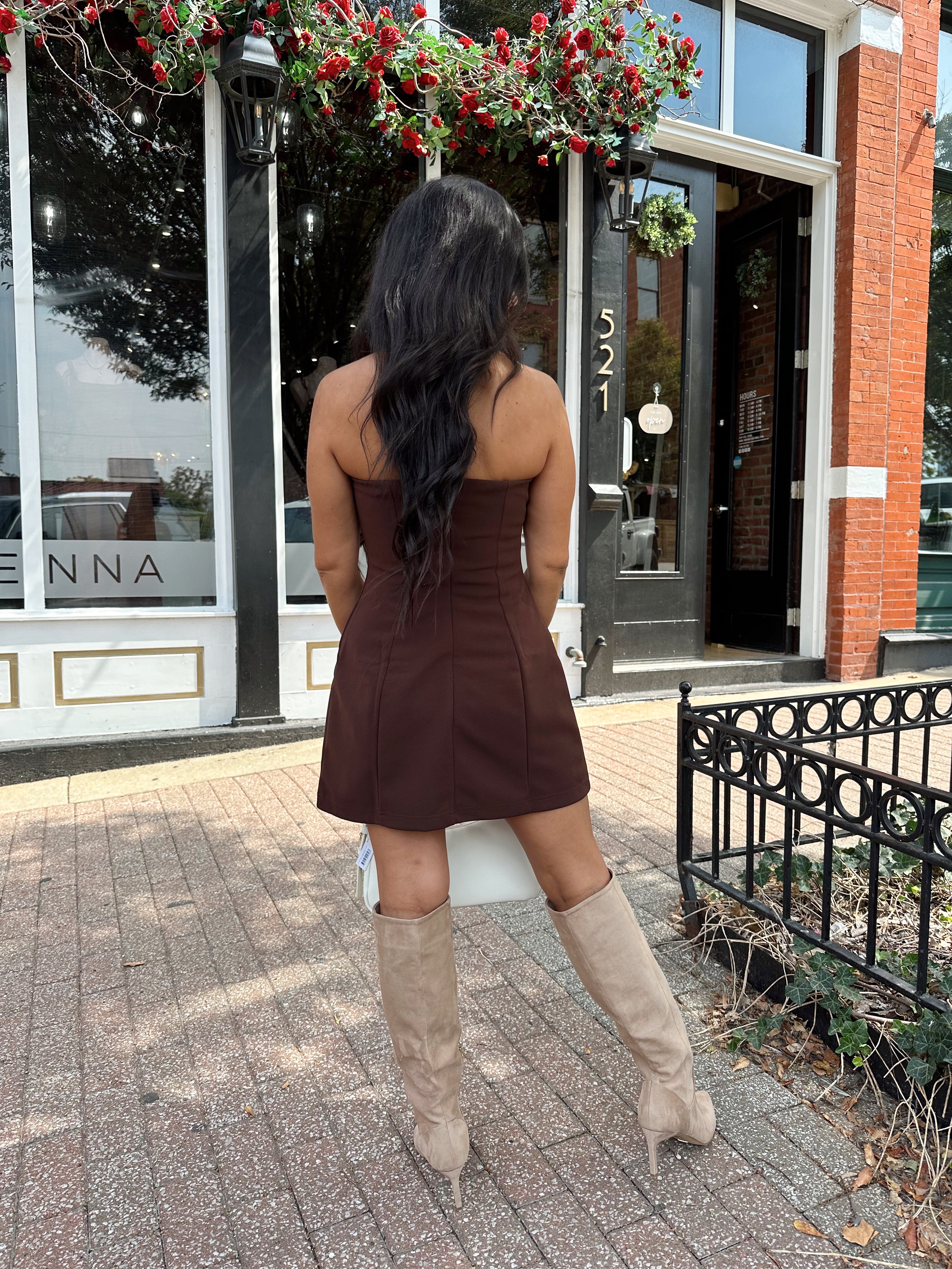 Woman wearing dark brown tailored mini dress with front pockets and built in shorts. 