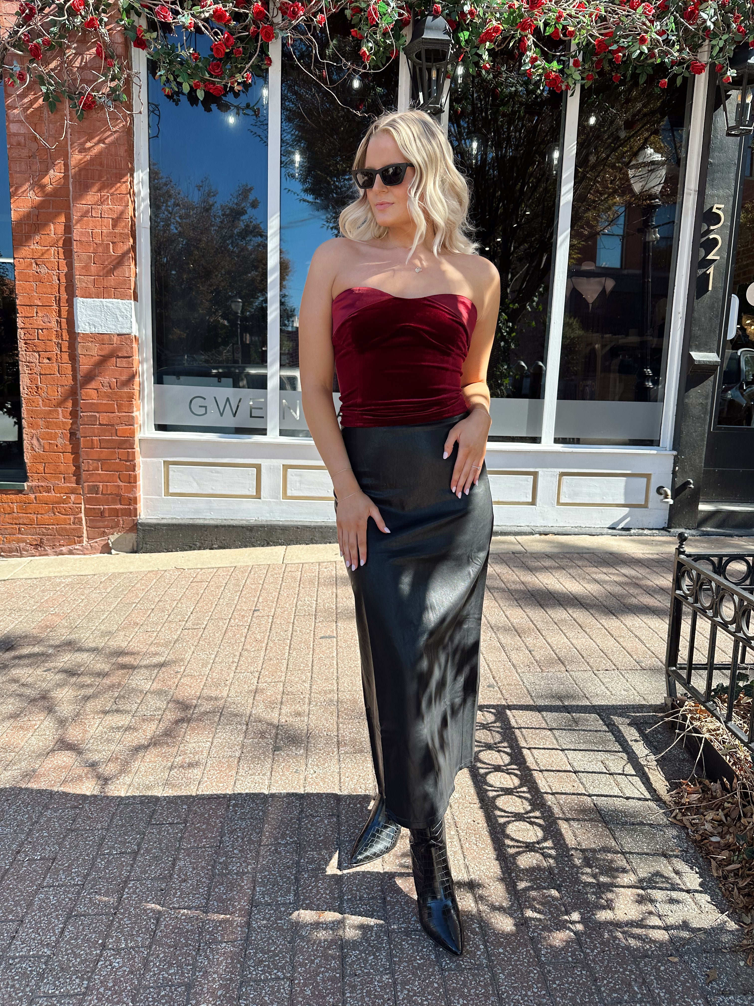 Woman wearing burgundy velvet strapless top with satin neckline. 