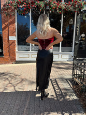 Woman wearing burgundy velvet strapless top with satin neckline. 