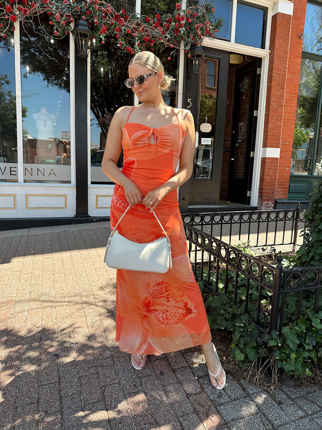 Woman wearing orange floral mesh maxi dress with criss-cross open back with adjustable spaghetti straps. 
