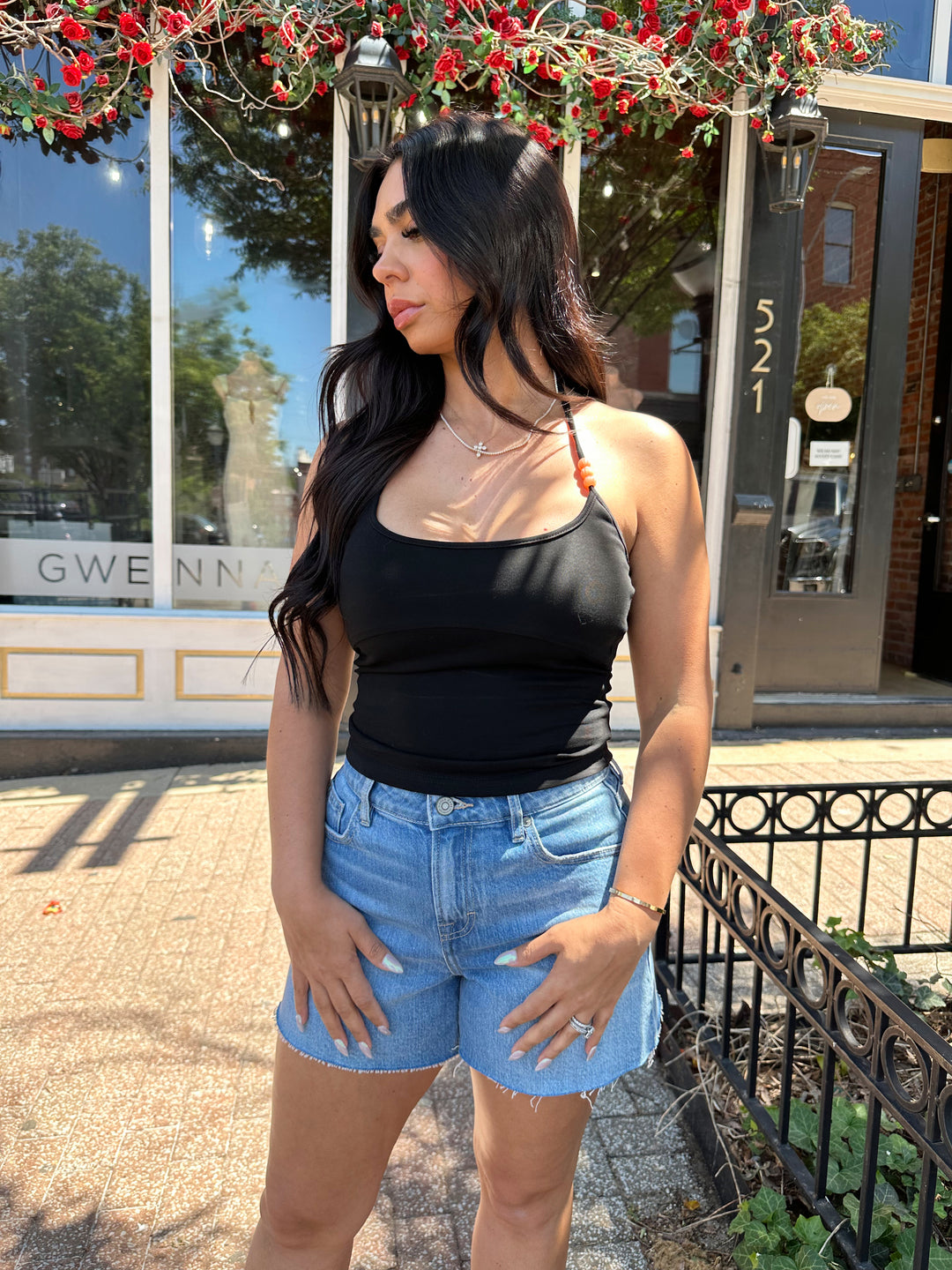 Woman wearing black halter top with beading detail, and denim shorts. 