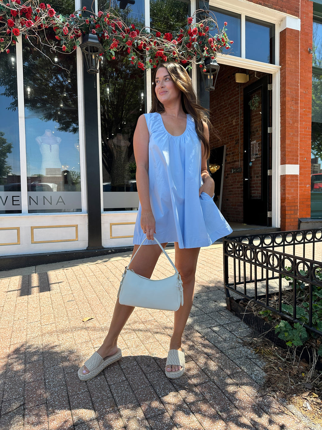 Woman wearing light blue, sleeveless, shift mini dress with gathering detail neckline. 