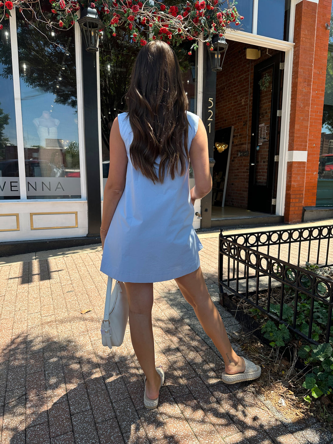 Woman wearing light blue, sleeveless, shift mini dress with gathering detail neckline. 