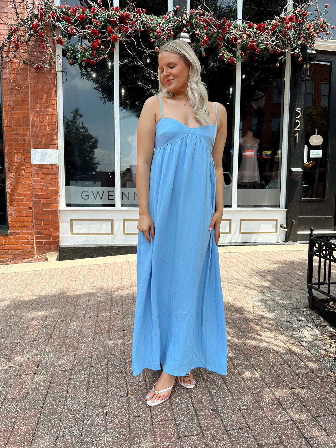 Woman wearing light blue maxi dress with sweetheart neckline and functional pockets