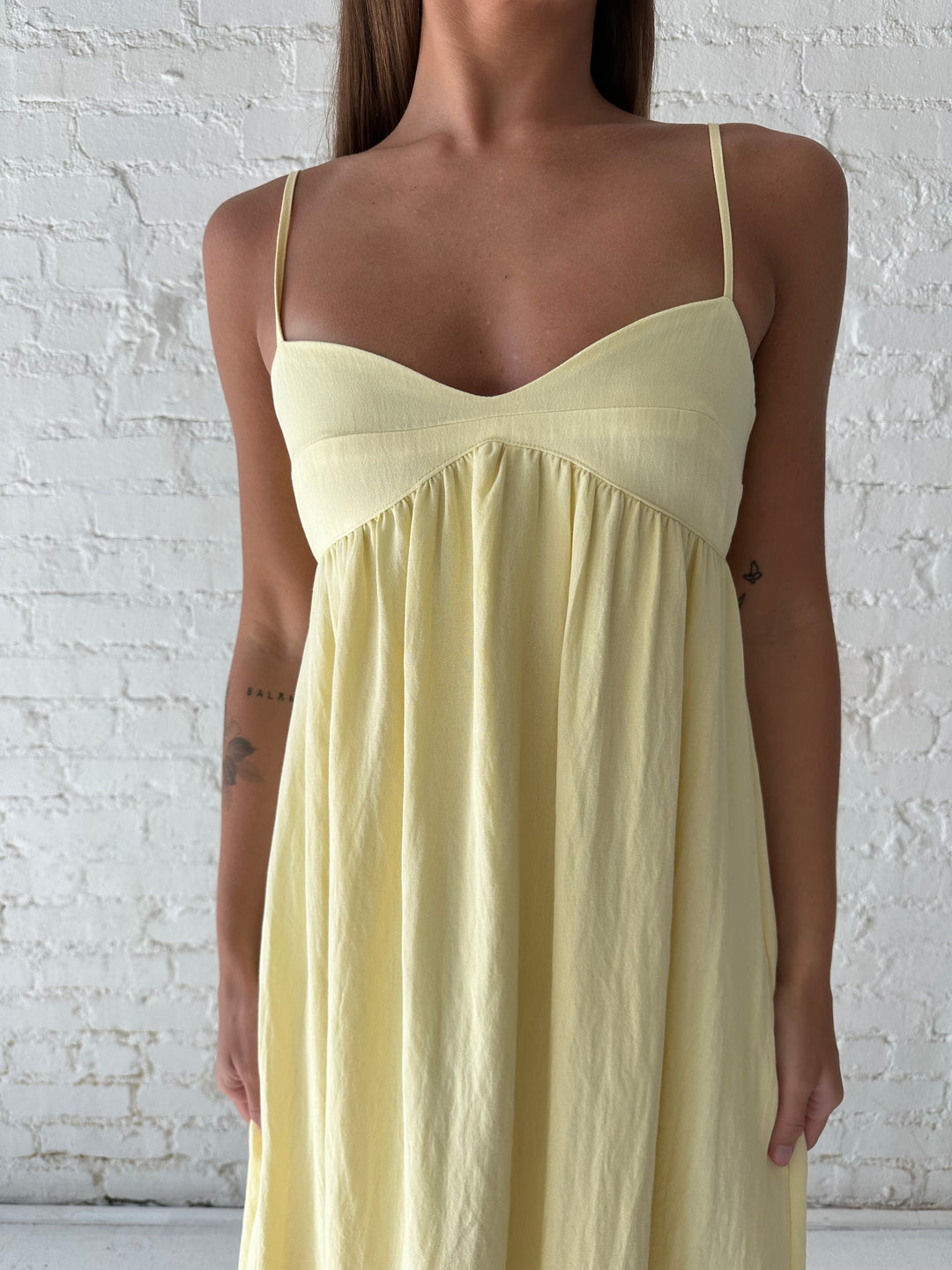 Woman wearing yellow maxi dress with sweetheart neckline, functional pockets, and adjustable straps.