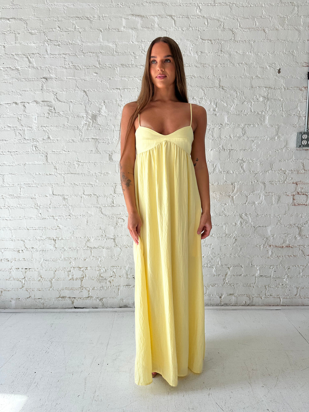 Woman wearing yellow maxi dress with sweetheart neckline, functional pockets, and adjustable straps.