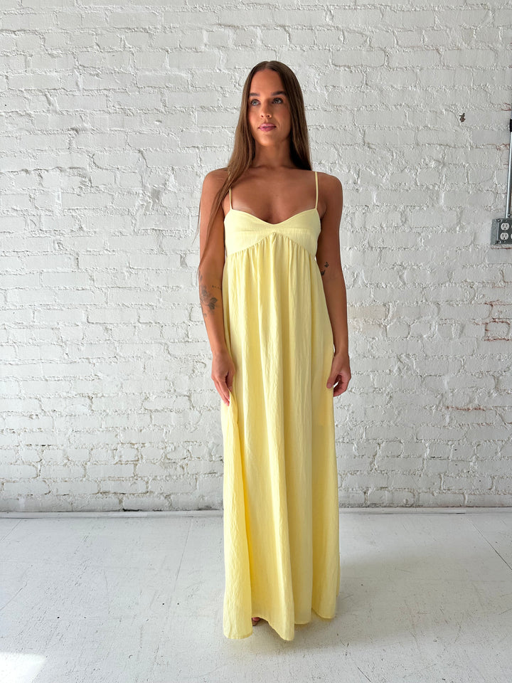 Woman wearing yellow maxi dress with sweetheart neckline, functional pockets, and adjustable straps.