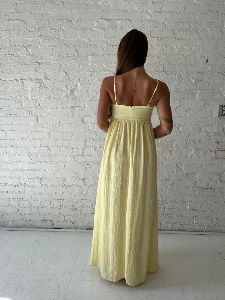 Woman wearing yellow maxi dress with sweetheart neckline, functional pockets, and adjustable straps.