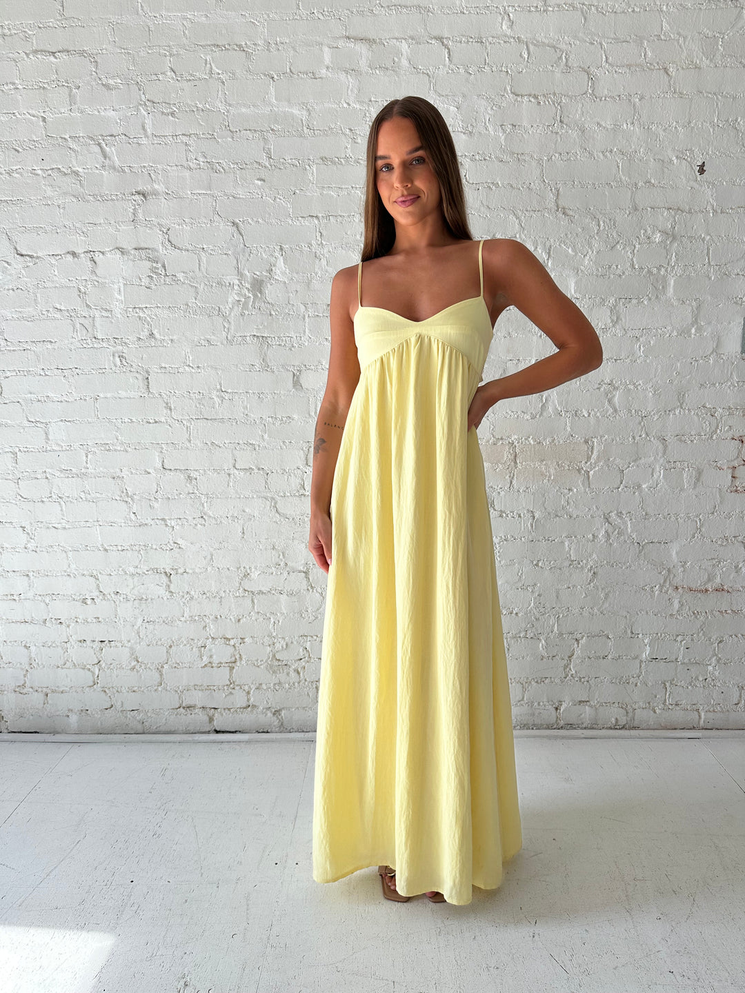 Woman wearing yellow maxi dress with sweetheart neckline, functional pockets, and adjustable straps.