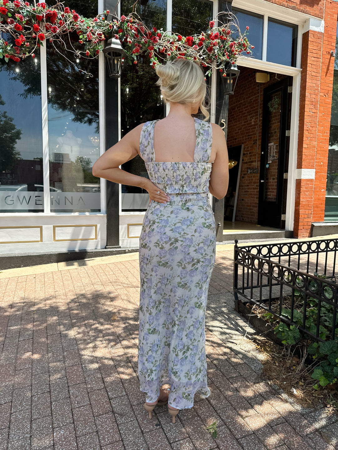 Woman wearing lilac floral two piece set with attachable neck scarf.