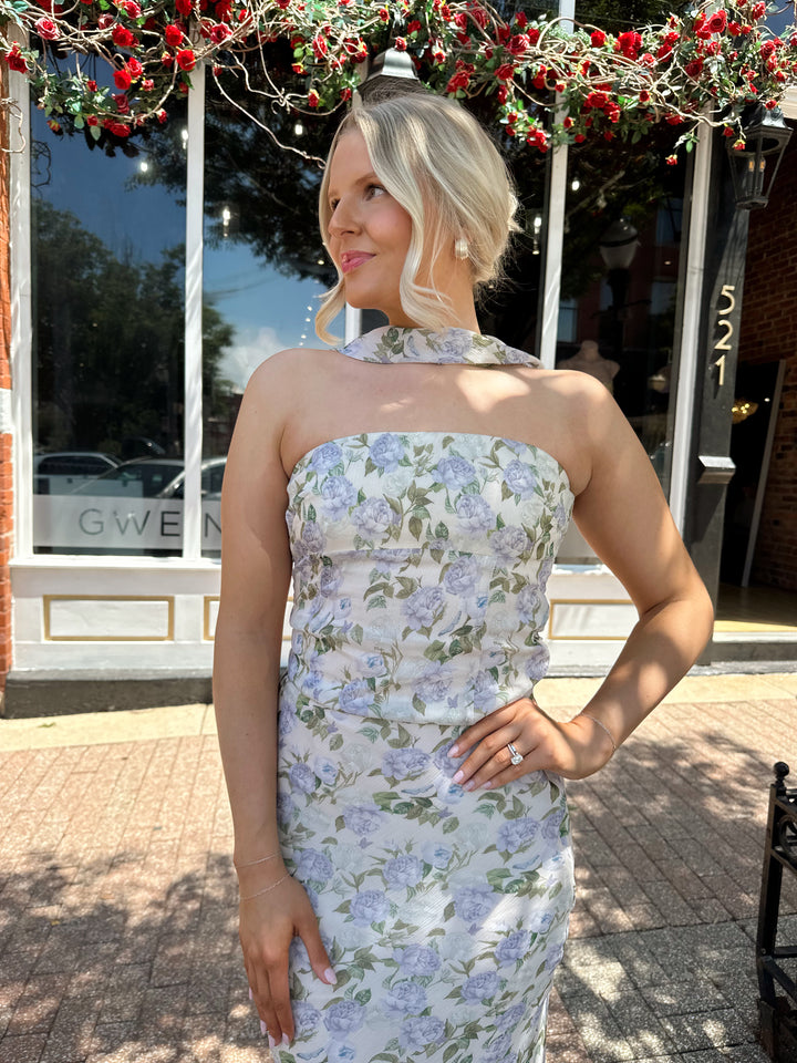 Woman wearing lilac floral two piece set with attachable neck scarf.