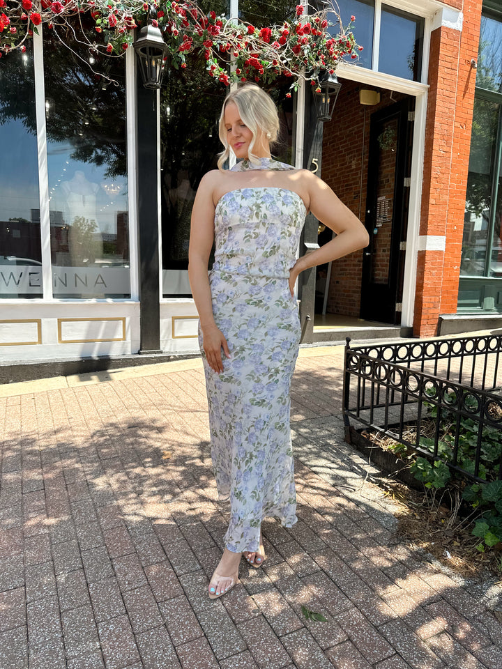 Woman wearing lilac floral two piece set with attachable neck scarf.