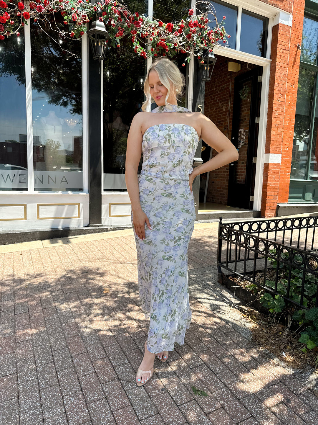 Woman wearing lilac floral two piece set with attachable neck scarf.