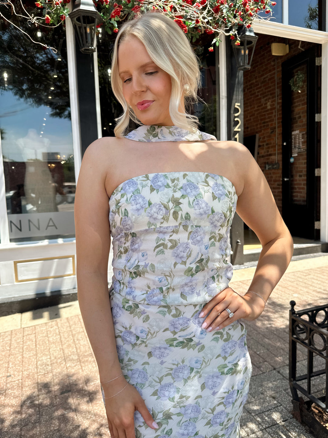 Woman wearing lilac floral two piece set with attachable neck scarf.