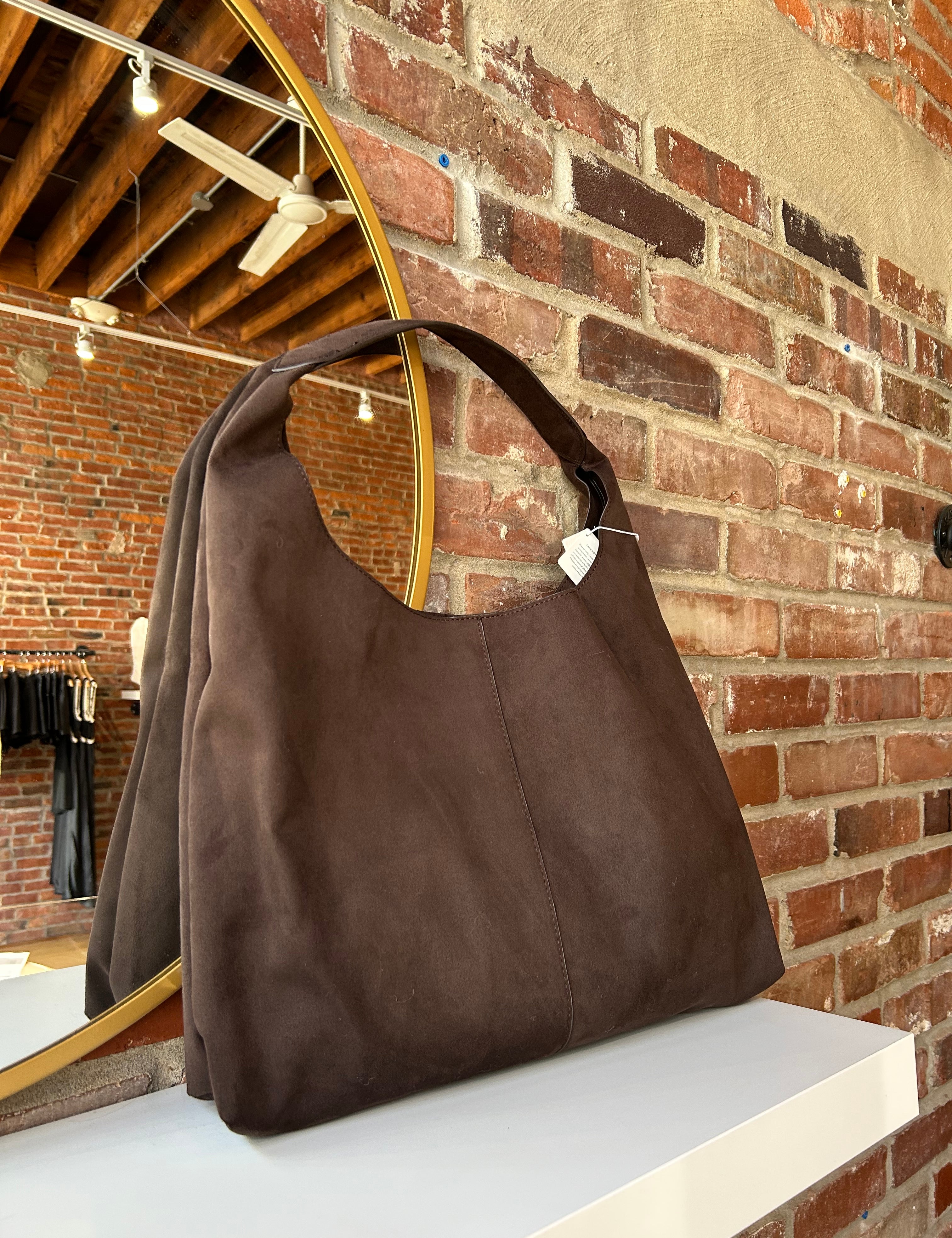 Dark brown suede shoulder bag with magnetic closure. 