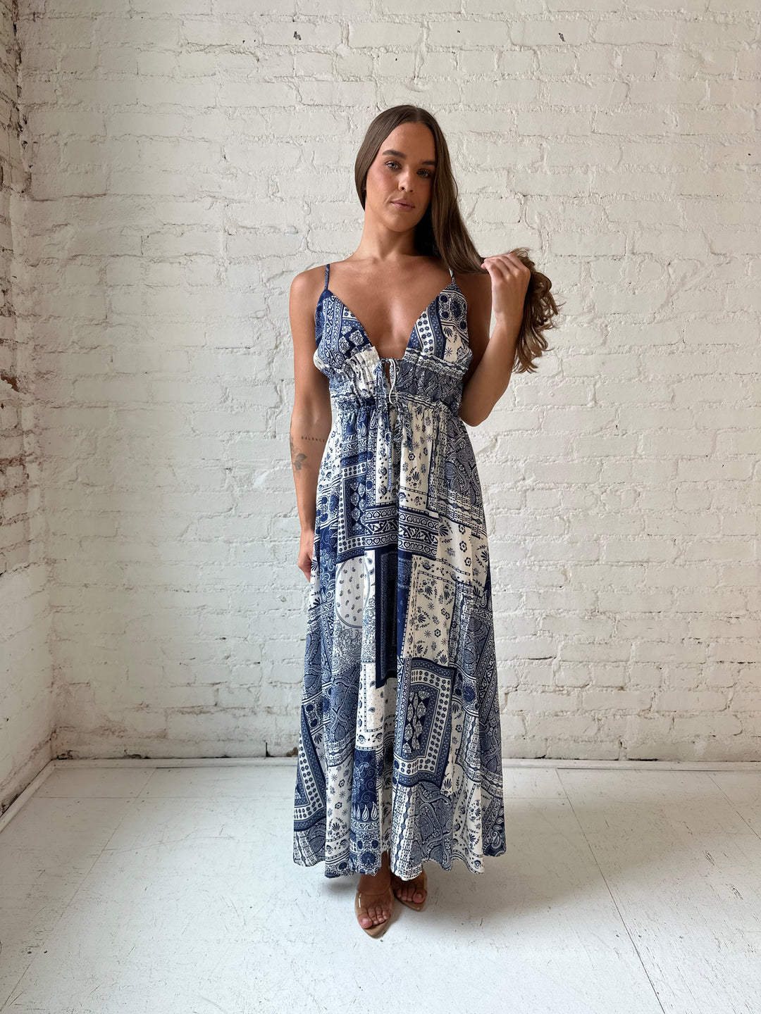 Woman wearing blue and white patchwork pattern midi dress with front tie detail.