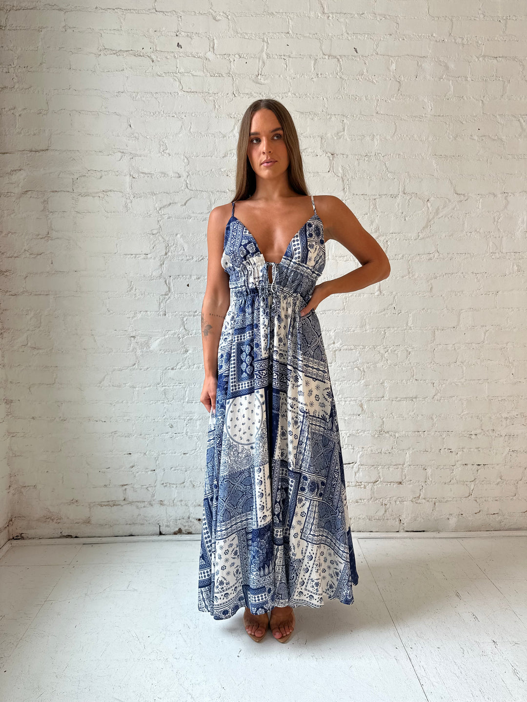 Woman wearing blue and white patchwork pattern midi dress with front tie detail.