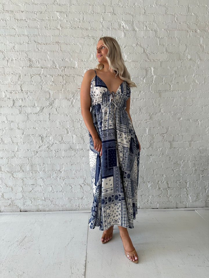 Woman wearing blue and white patchwork midi dress with adjustable straps.