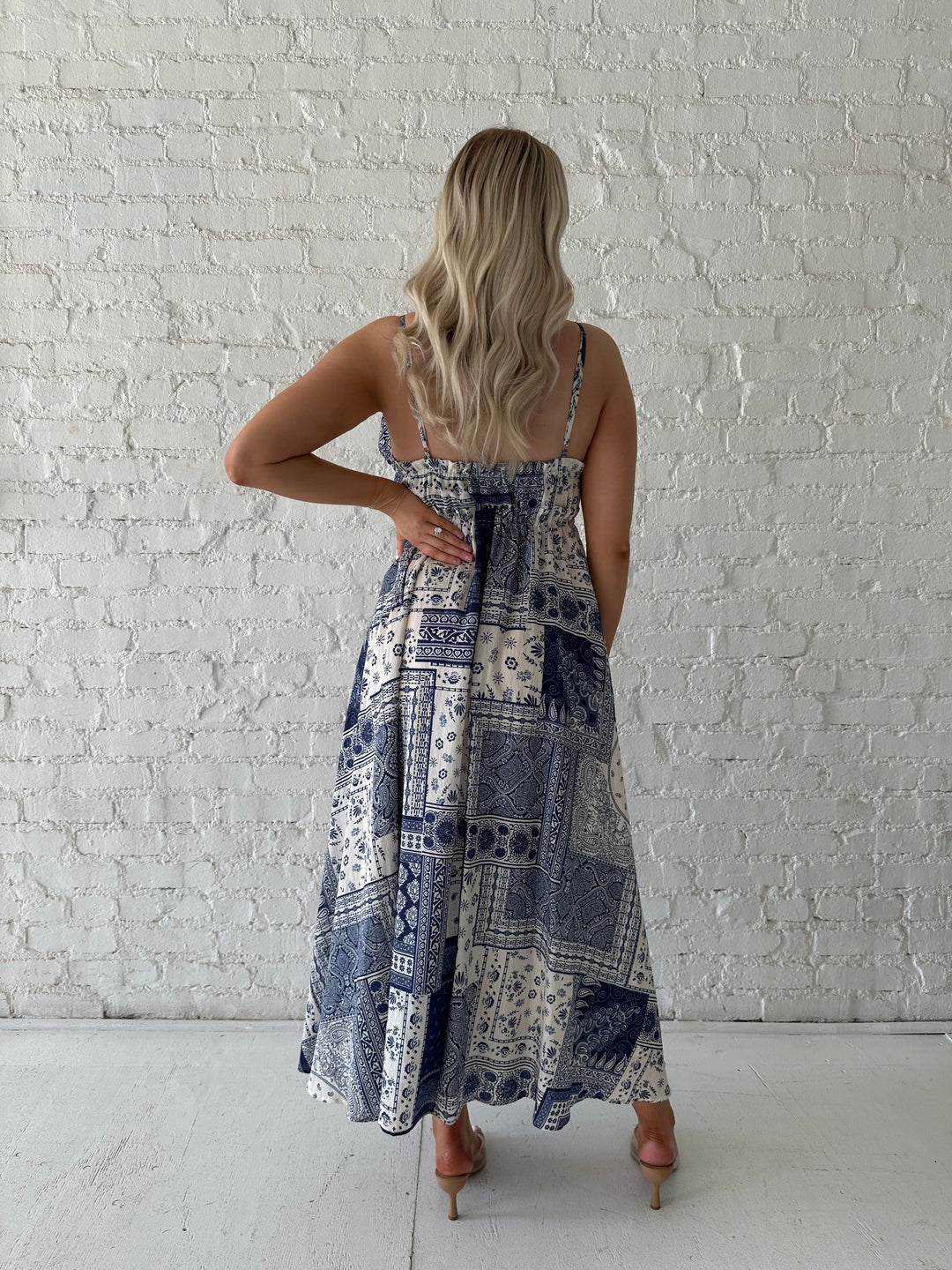 Woman wearing blue and white patchwork midi dress with adjustable straps.