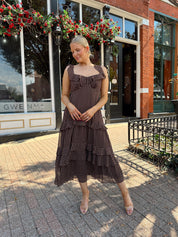 Woman wearing brown polka dot ruffle tiered midi dress. 
