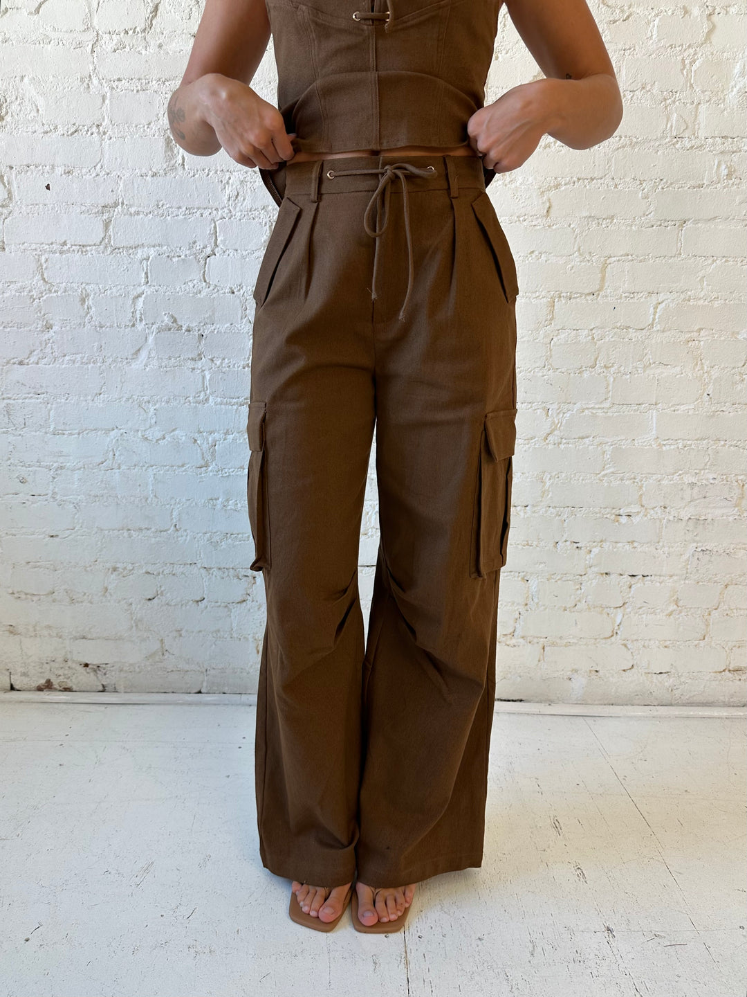 Woman wearing brown two piece cargo pant set with halter neck, and lace up front detail. 