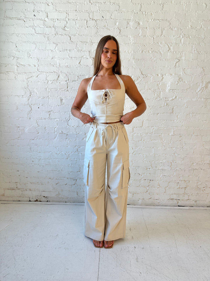 Woman wearing taupe colored two piece cargo set with halter neckline with lace up front detailing. 