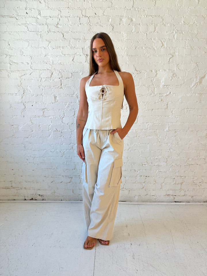 Woman wearing taupe colored two piece cargo set with halter neckline with lace up front detailing. 