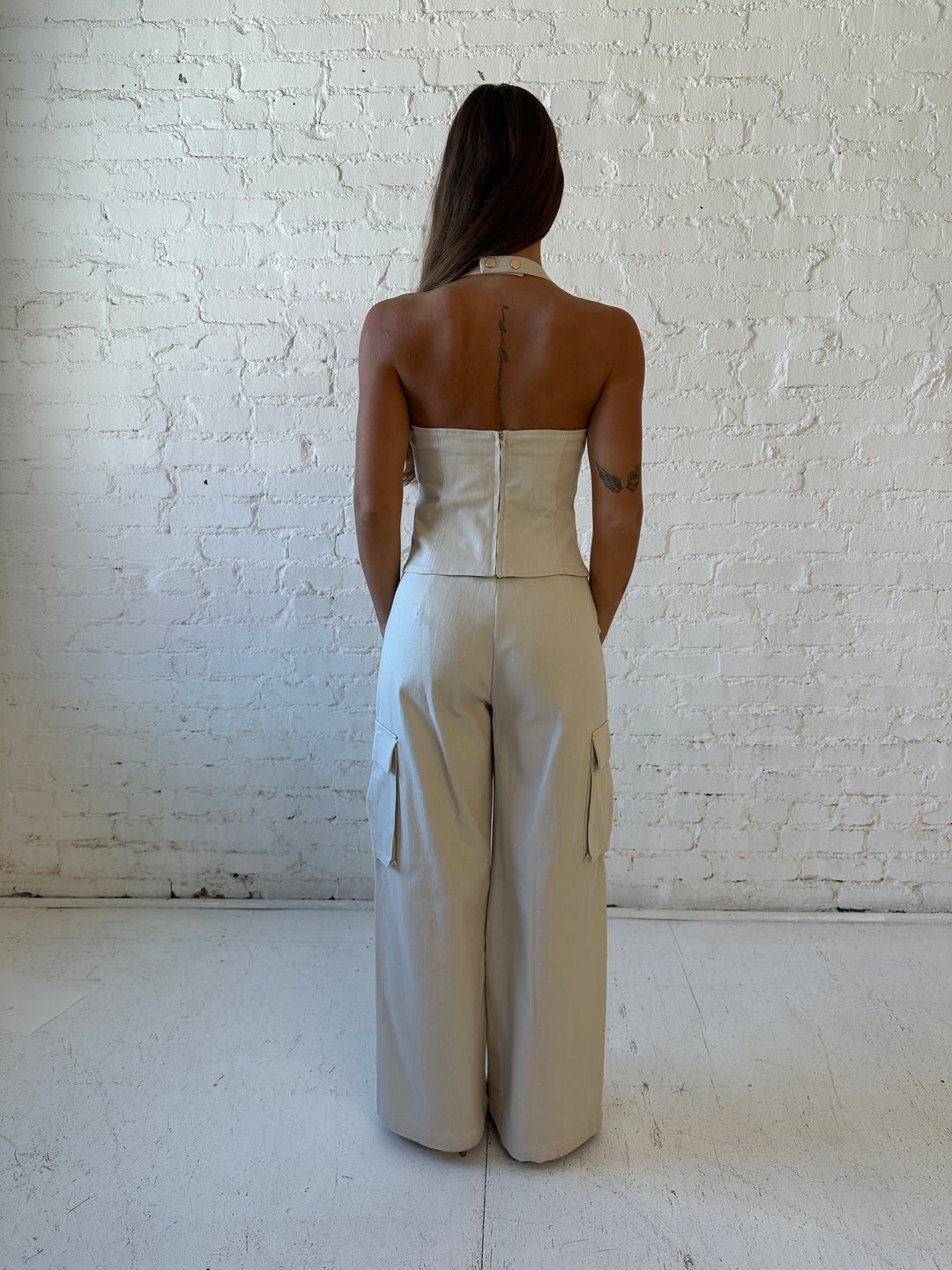Woman wearing taupe colored two piece cargo set with halter neckline with lace up front detailing. 
