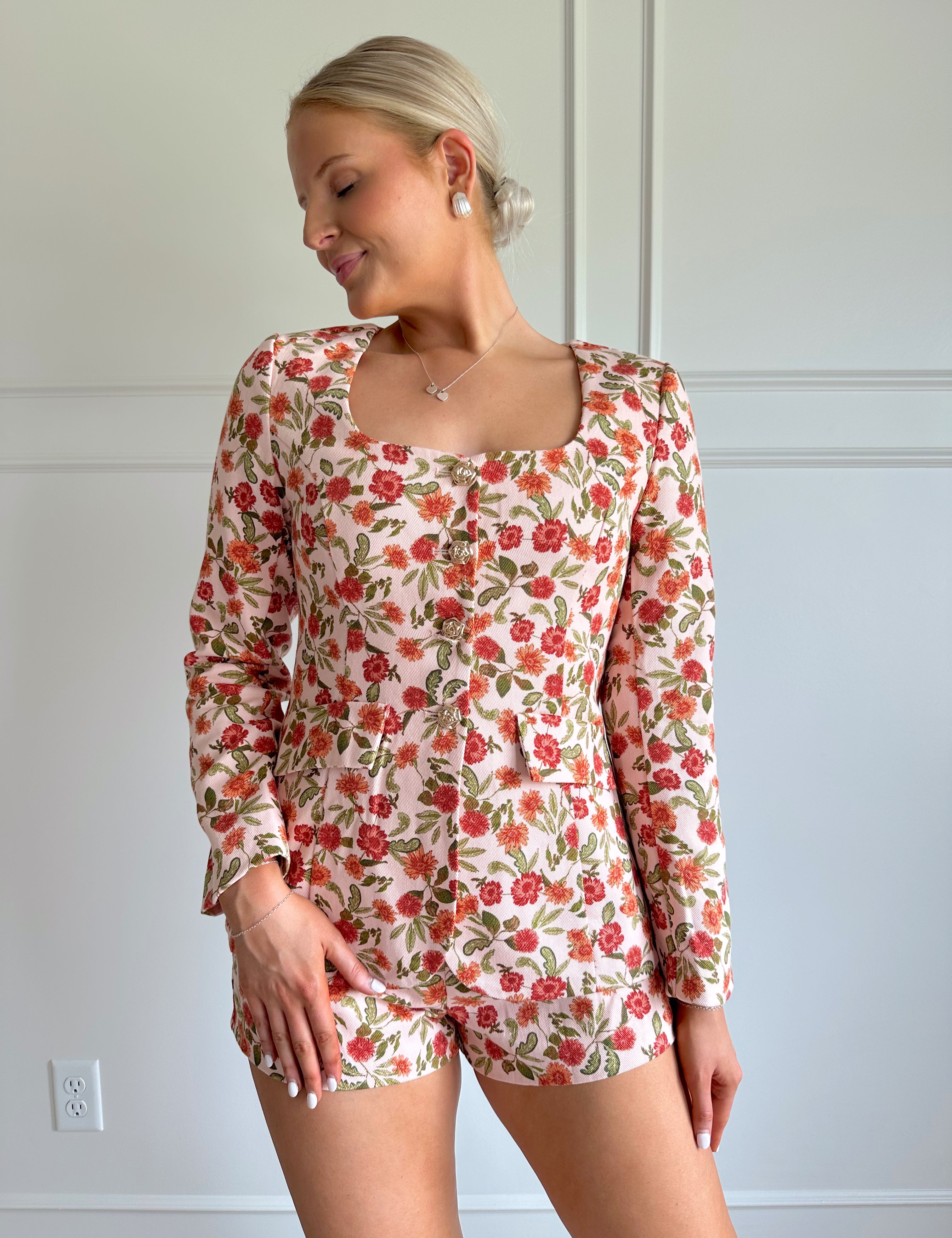 Orange floral tailored long sleeve romper with gold button detailing. 