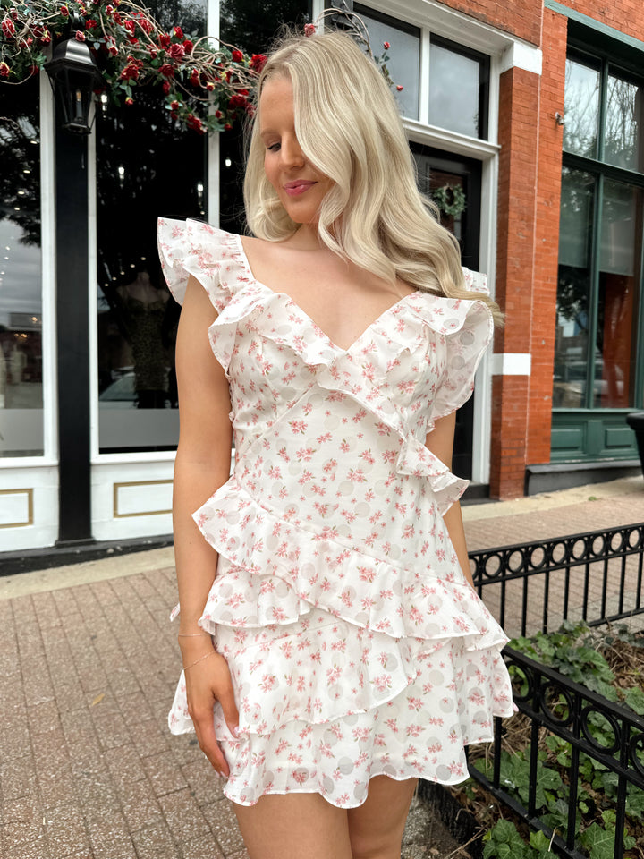 Woman wearing pink floral mini dress with ruffle tiered detailing,