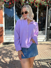 Woman wearing lavender knit button up cardigan with denim skirt. 