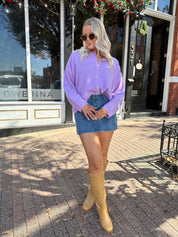 Woman wearing lavender knit button up cardigan with denim skirt. 