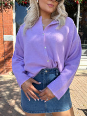 Woman wearing lavender knit button up cardigan with denim skirt. 