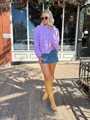 Woman wearing lavender knit button up cardigan with denim skirt. 