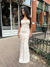 Woman wearing champagne floral satin two piece set with corset top and maxi skirt. 