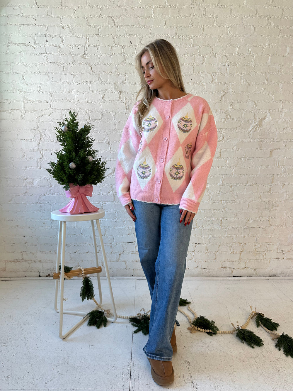 Woman wearing pink and white button down cardigan with embroidered ornaments. 