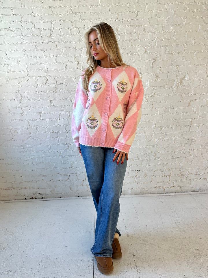 Woman wearing pink and white button down cardigan with embroidered ornaments. 