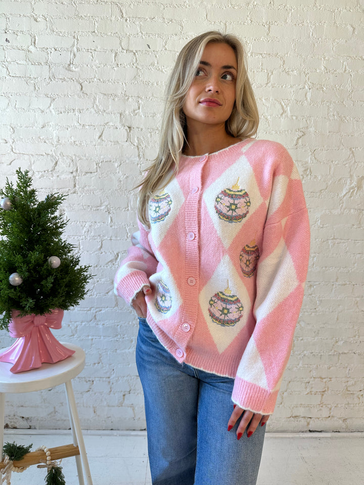 Woman wearing pink and white button down cardigan with embroidered ornaments. 