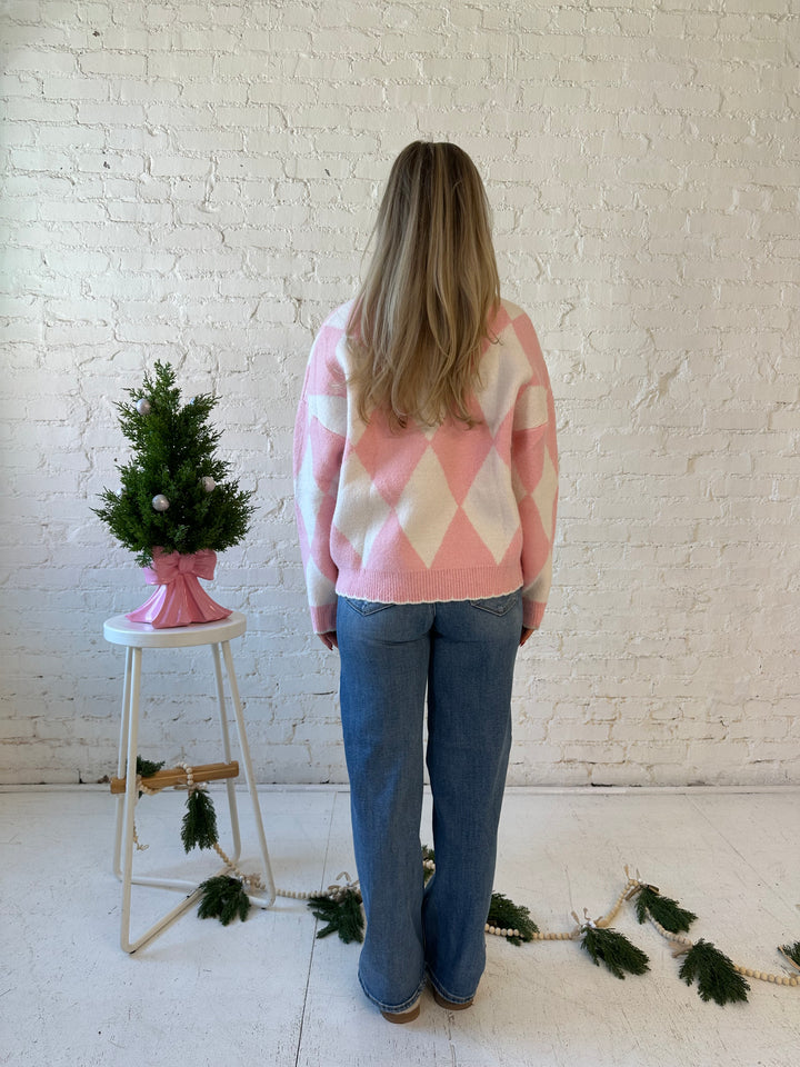 Woman wearing pink and white button down cardigan with embroidered ornaments. 