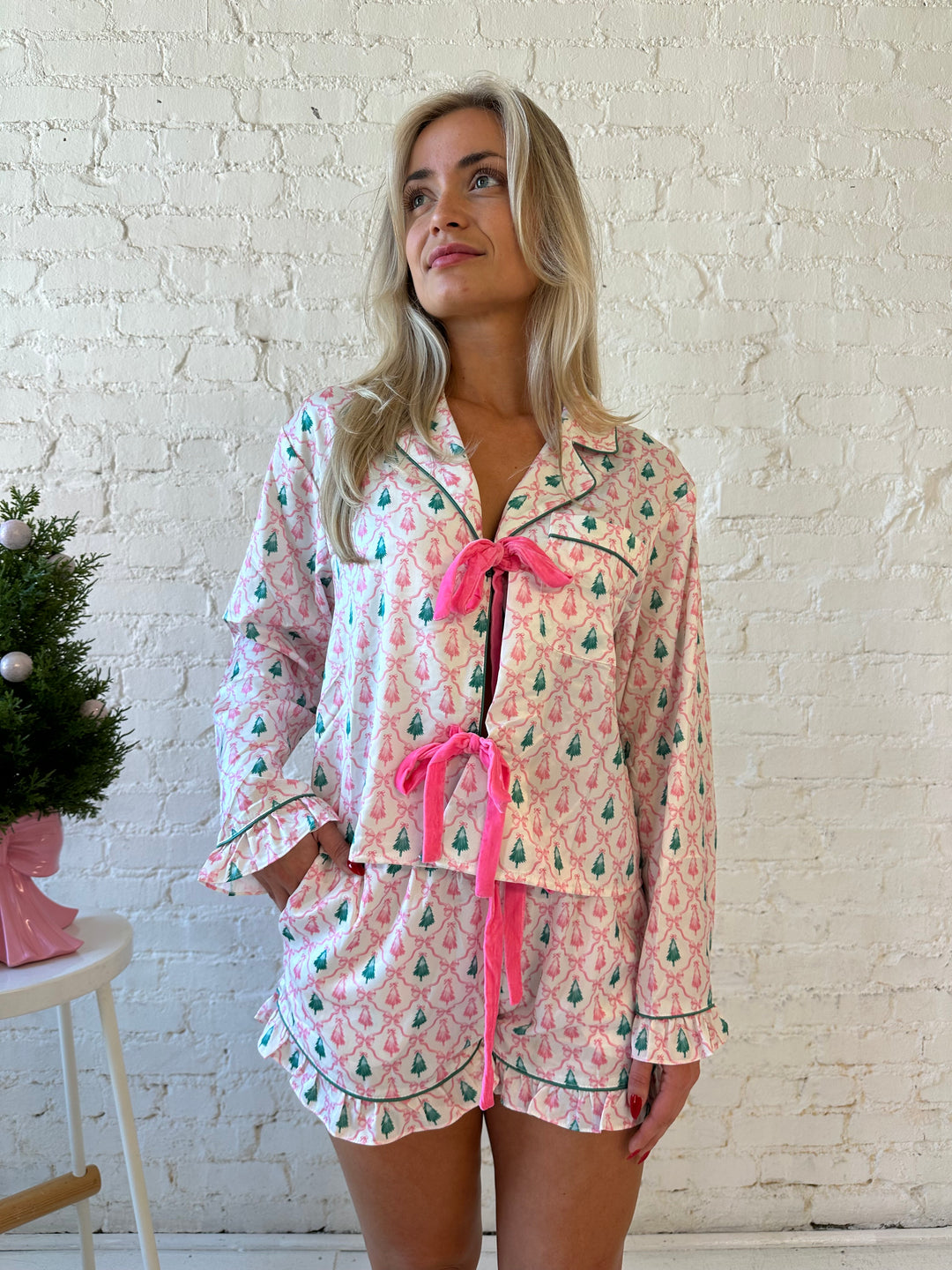 Woman wearing green and pink Christmas tree pattern pajamas with pink velvet front tie closure. 