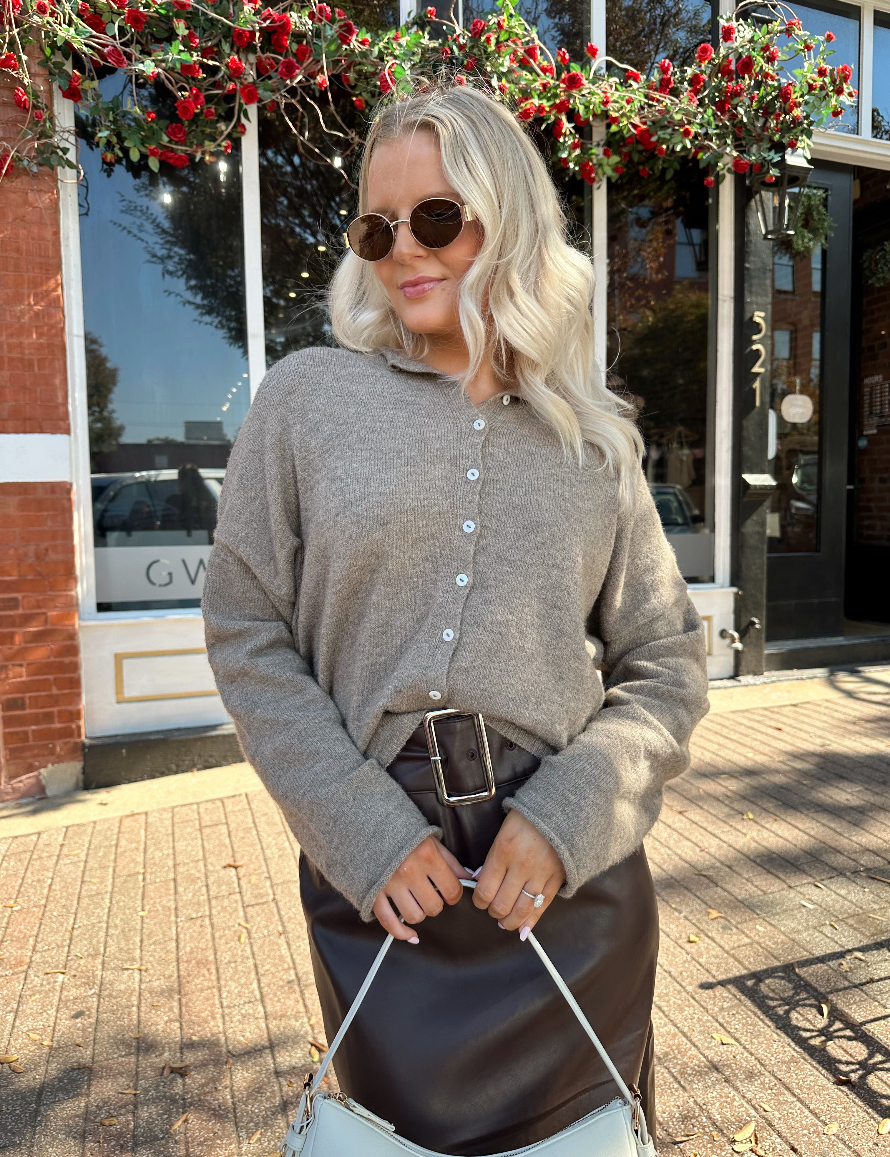 Woman wearing mocha knit button down cardigan with brown leather belted midi skirt.