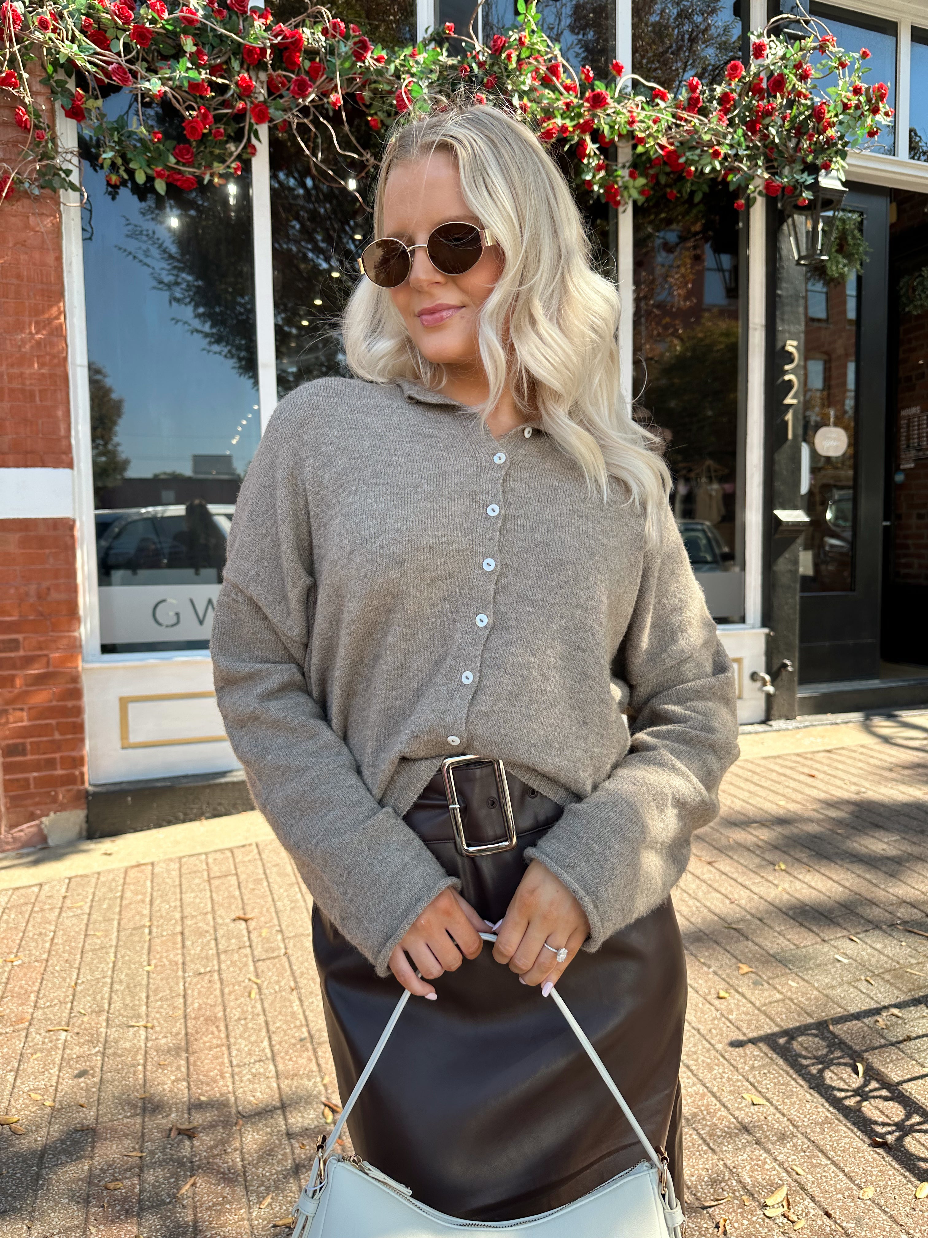 Woman wearing mocha knit button down cardigan with brown leather belted midi skirt.