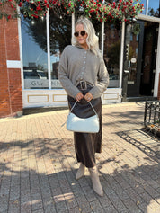 Woman wearing mocha knit button down cardigan with brown leather belted midi skirt.
