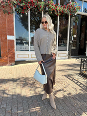 Woman wearing mocha knit button down cardigan with brown leather belted midi skirt.
