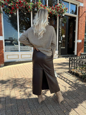 Woman wearing mocha knit button down cardigan with brown leather belted midi skirt.