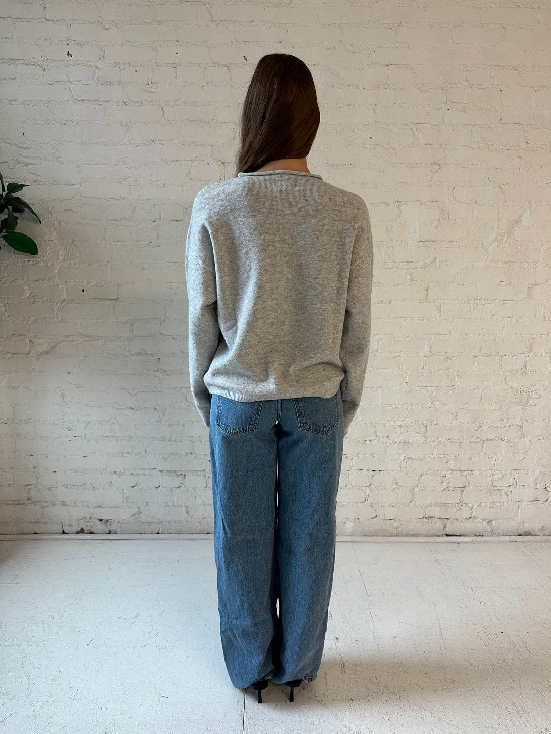 Woman wearing light grey knit button down cardigan with medium wash jeans. 