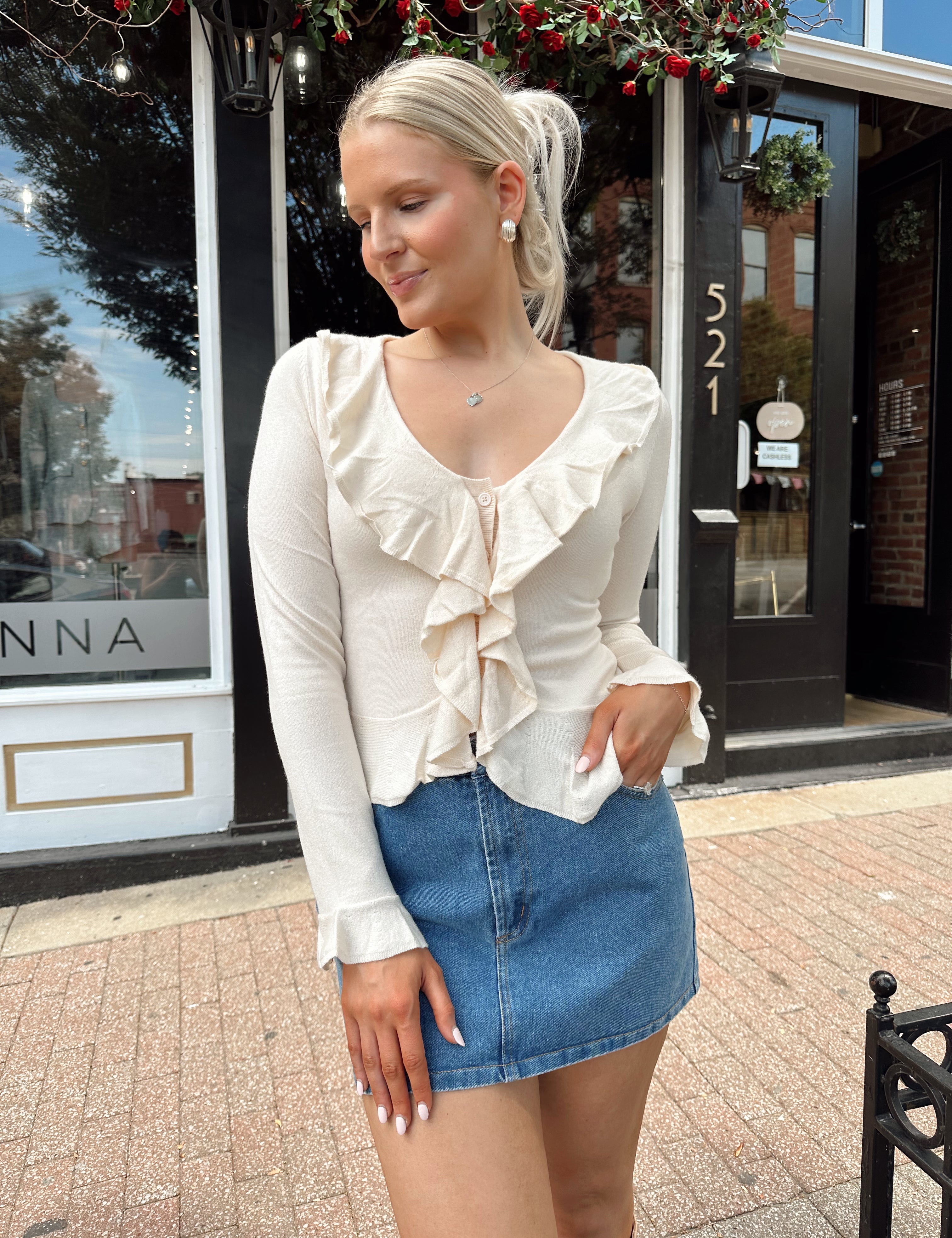 Cream colored knit long sleeve top with button detailing and ruffle neckline