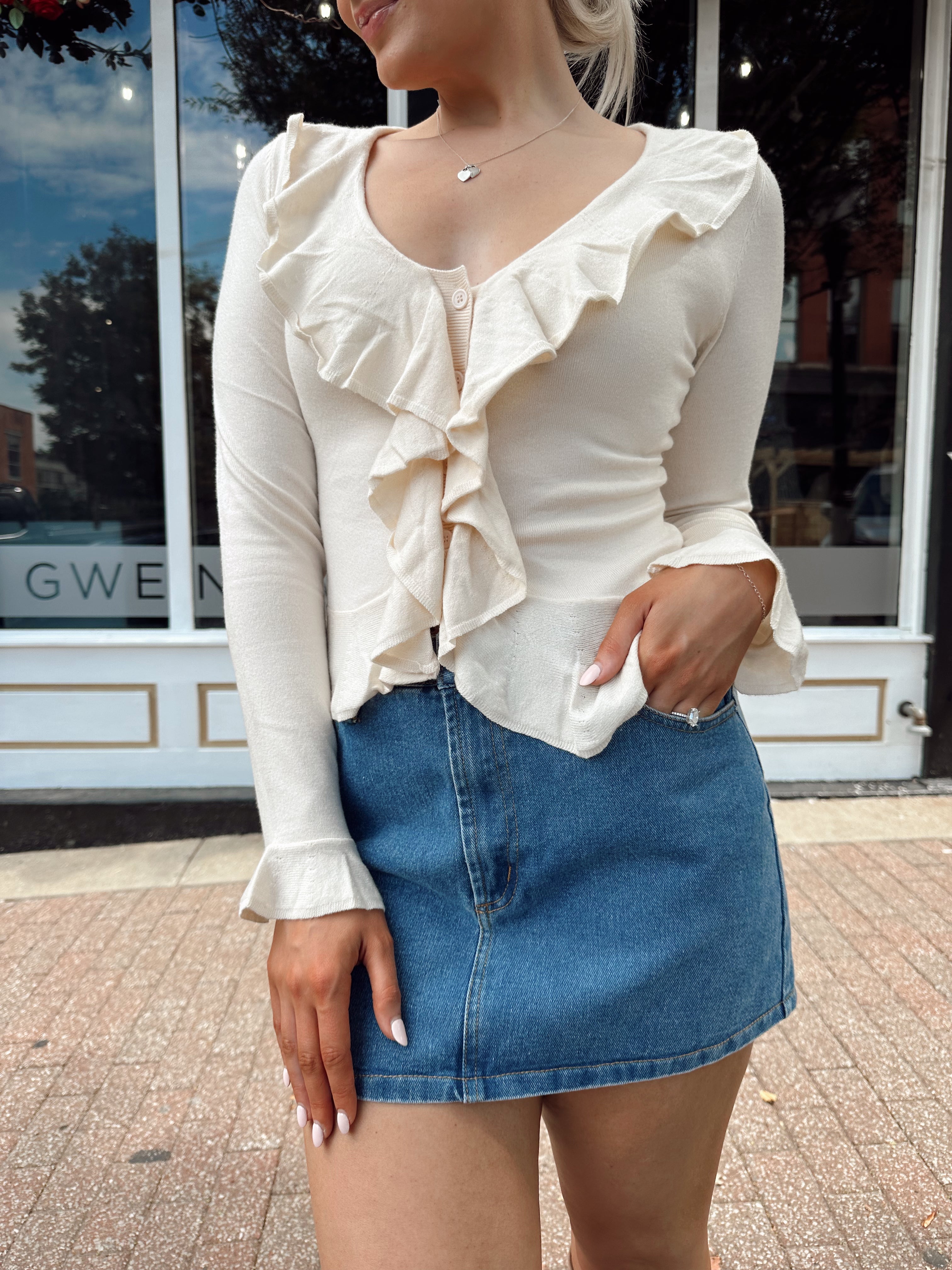 Cream colored knit long sleeve top with button detailing and ruffle neckline